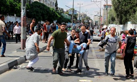 Palestinian men carry an injured man following an Israeli military strike on a UN school in Rafah, in the southern Gaza Strip. Photograph: Rex Features